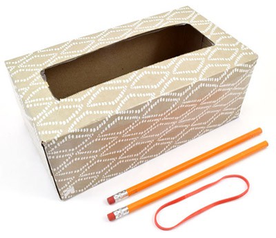 An empty tissue box, two pencils, and a rubber band