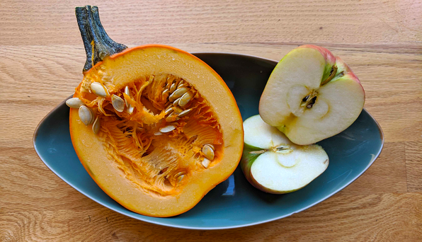 Tray containing cut apple, pumpkin, and lemon with their seeds