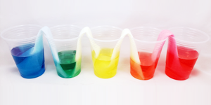 Strips of paper towel connect different colored liquids in five plastic cups in this science activity