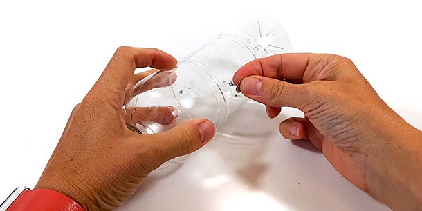 A hole is pierced into a plastic bottle with a thumbtack.