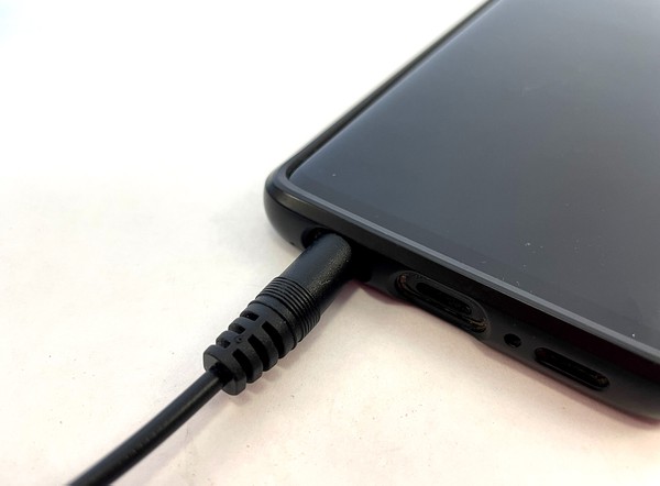 audio cable plugged into headphone jack of cell phone. 