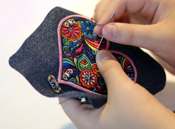 An intricately designed heart is sewn onto a fabric square