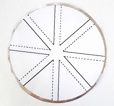 A paper windmill template is taped to an aluminum circle