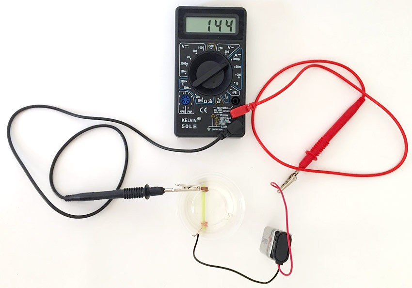 Alligator clips attach multimeter probes to a battery and conductivity sensor