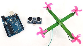 A popsicle stick drone next to an ultrasonic distance sensor and an Arduino