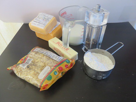 The ingredients required to make macaroni and cheese: elbow pasta, cheese, butter, milk, pepper, and flour.