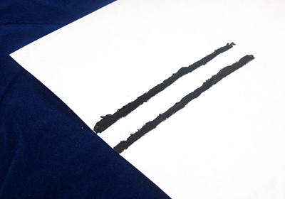 Two parallel lines of black paint on a piece of paper
