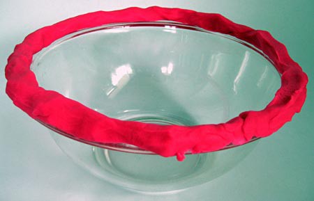 A thick layer of pink play-doh surrounds the lip of a glass bowl