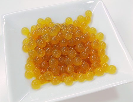 Small amber colored spheres piled in a bowl that contain green tea