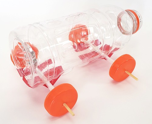 Plastic bottle with wheels and axles attached, made from straws, skewers, and bottle caps