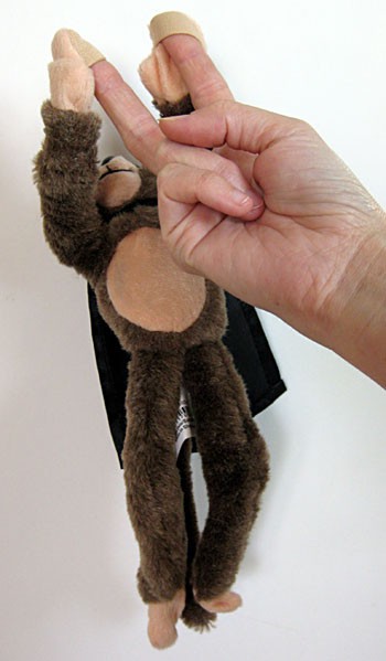 Two fingers attach to the hands of a stuffed toy monkey