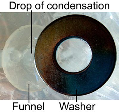 Image of a washer creating a low spot for condesation to form on saran wrap that is directly over a collection funnel
