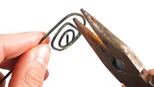 Pliers forming a spiral out of a metal wire.