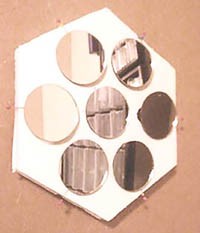 Seven circular mirrors mounted onto a hexagonal foam board
