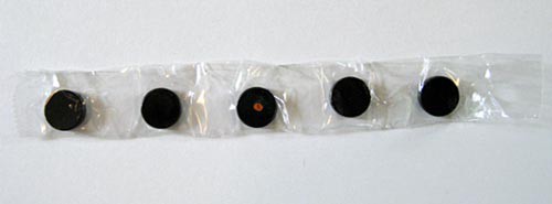 Five circular magnets are lined up in alternating polar directions and laid on a long strip of clear tape