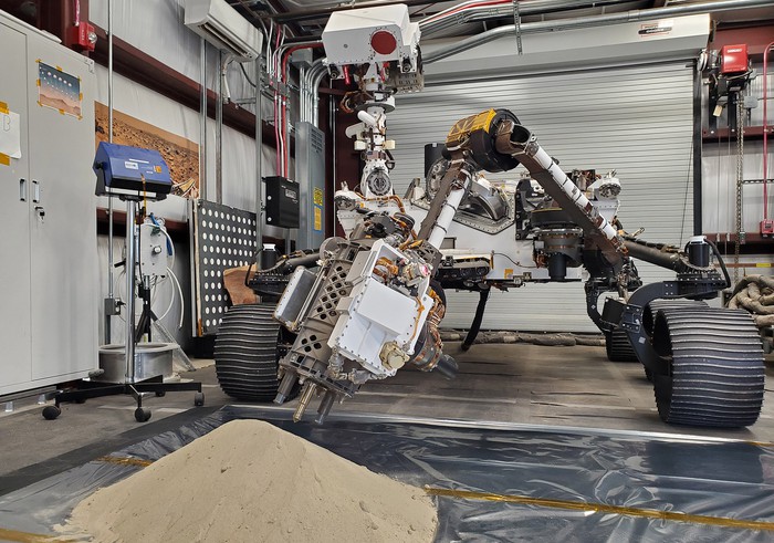 Optimism, a replica of the Mars rover Perseverance, collecting soil samples in a lab on Earth 