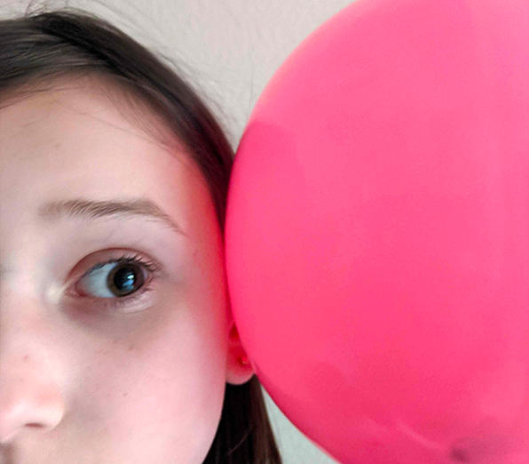 Student holding balloon next to ear