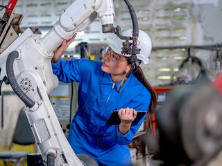 female factory working holding tablet and doing robot maintenance
