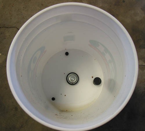 A plastic bucket with holes drilled in the bottom