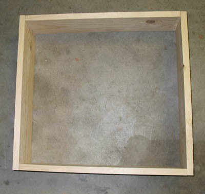 Four wooden boards are nailed together to create a square wooden frame
