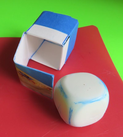 A cardboard carton and hard-boiled egg both in the shape of a cube