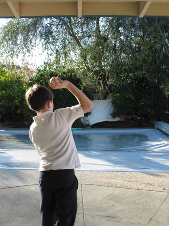 A boy standing upright tries to throw a pitch without taking any steps
