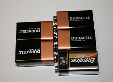 Five 9-volt batteries are connected by pressing their terminals together in an alternating pattern