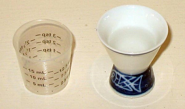 A cup of water next to a small measuring cup