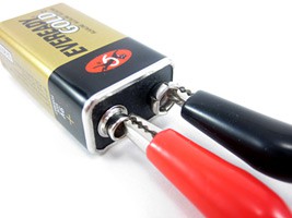 Two alligator clips attached to the terminals of a nine volt battery