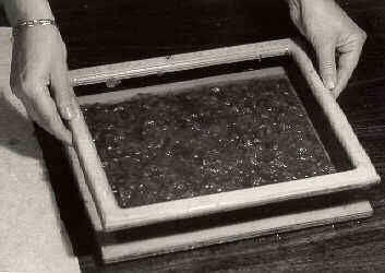 Black and white photo of a wooden framed box filled with a thin layer of paper pulp