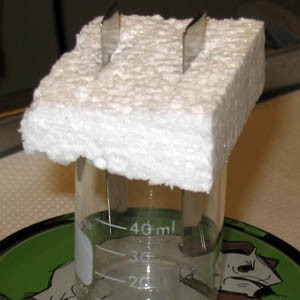 Two strips of metal stick through a block of styrofoam in the beaker 