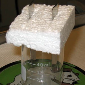 Two strips of metal stick through a block of styrofoam in the beaker