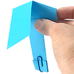 Hand holding paper whirlybird with a paperclip at the bottom