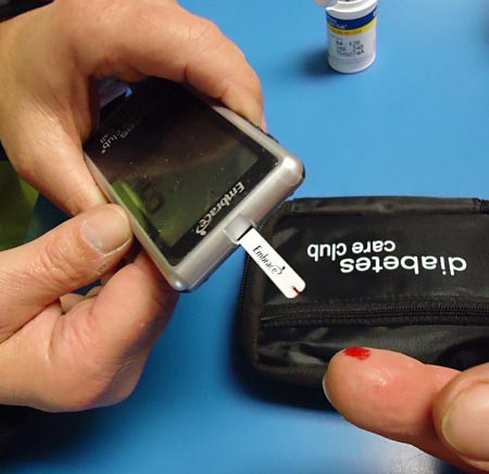 Putting a drop of blood on the test strip of a glucose meter