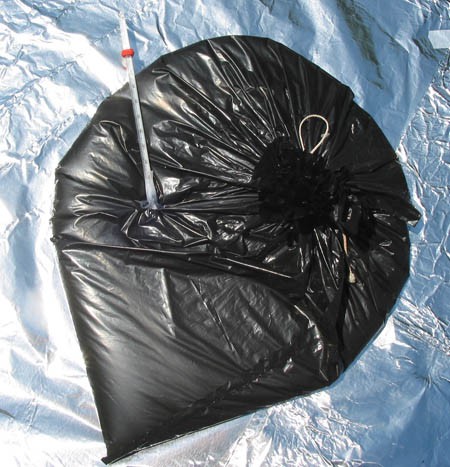 A thermometer is inserted into an inflated black plastic bag