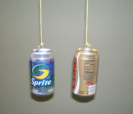 Two soda cans suspended by strings with a gap in between