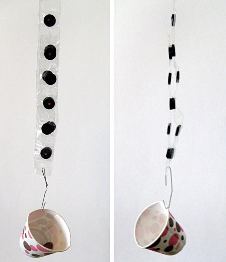Two strips of tapes imbued with circular magnets are pressed together while one strip has a paper cup attached to the end