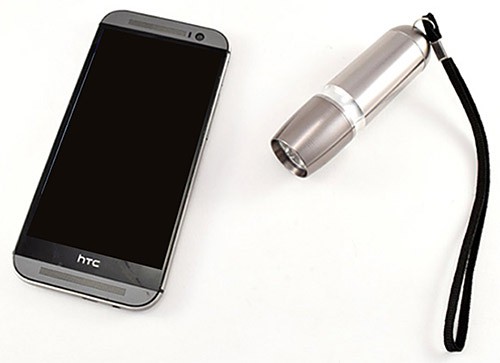 A smartphone next to a flashlight