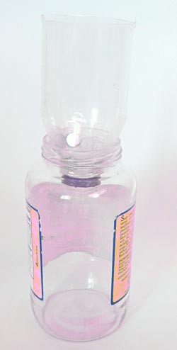 The top half of a plastic bottle is used as a funnel over a container and magnets are taped to the outside neck of the funnel