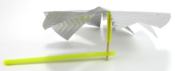 A pinwheel is made from a cut aluminum plate, straws and a toothpick