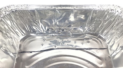 End section of the aluminum pan showing the marked line as well as the poked holes in the bottom of the pan behind the line.