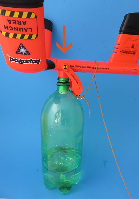 A bottle rocket resting on the ground and a launcher pushed upside down in the bottle spout .