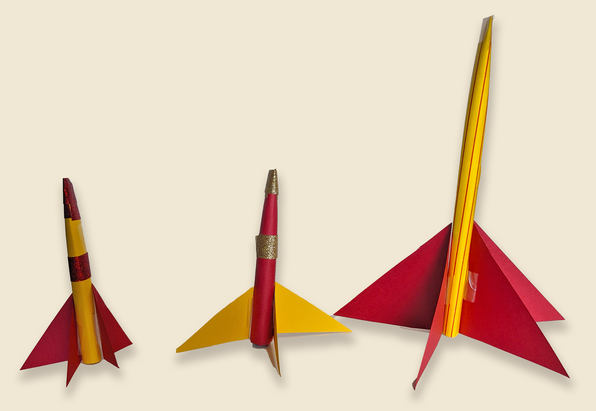 Three red and gold paper rockets in varying sizes