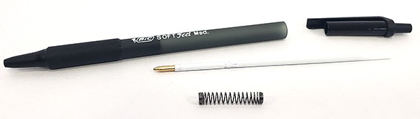 A disassembled retractable pen, revealing the spring inside