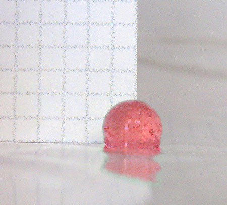 Photo of graphing paper placed behind a translucent red sphere