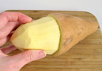 Whole sweet potato with the bottom half peeled
