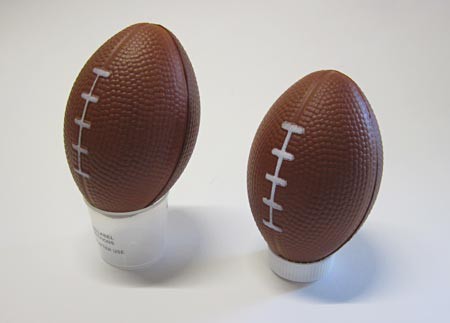 Small footballs resting on medicine cup or small bottle cap