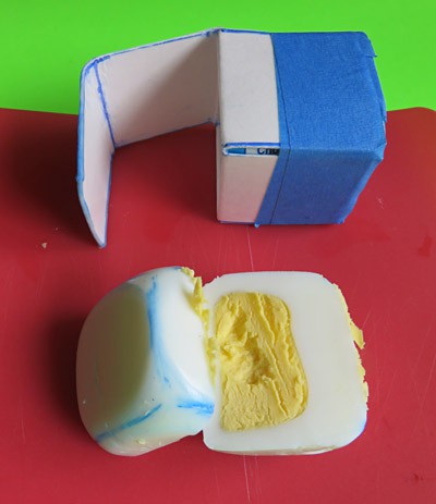 A cube shaped hard-boiled egg is cut in half and has a square yolk