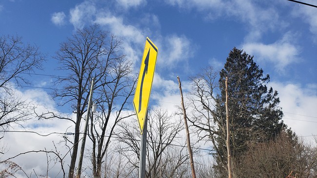 A picture of a curve sign taken from an extreme angle, resulting in a skewed, narrow diamond shape in the image