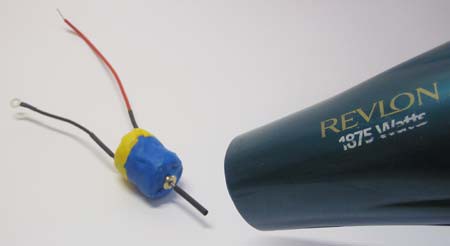 A hair dryer securing heat shrink tubing to the shaft of a DC motor